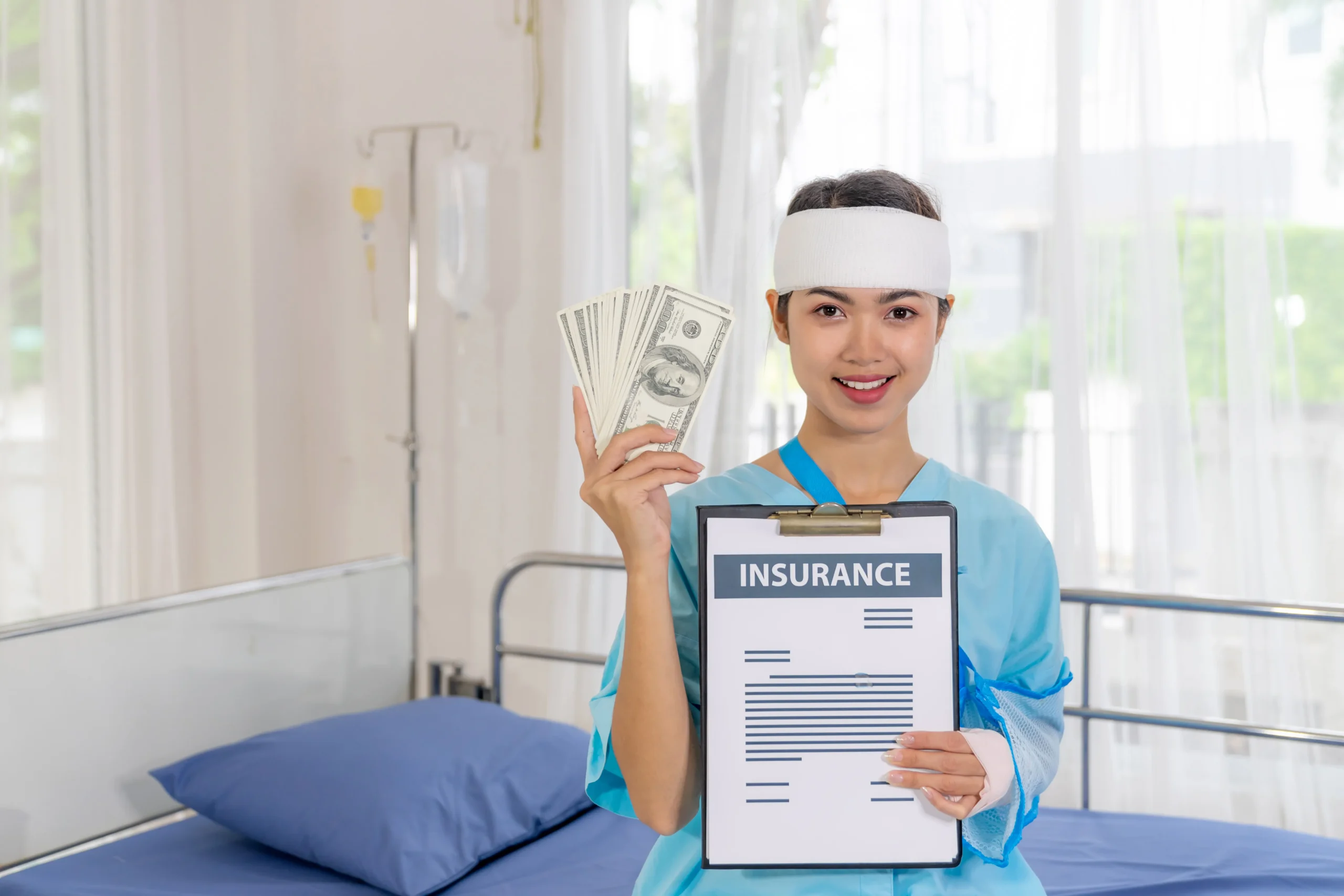 A person in a hospital gown and head bandage holds up a stack of US dollar bills in one hand and an insurance document on a clipboard in the other, smiling in a hospital room with a bed and medical equipment. They appear to be satisfied, potentially due to effective medical billing and coding services.